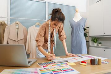 Fashion design concept, Asian female fashion designer sketching new clothes collection in atelier