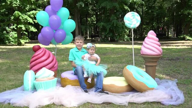 Slow Motion cute little girl and boy with big cake and lollipops on nature