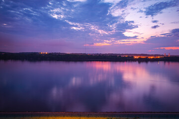 Tranquil vibrant sunset landscape over the Mississippi River and illuminated riverbank in Moline,...