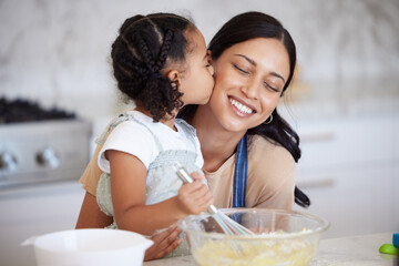 Happy latin mother and daughter baking and sharing a kiss while bonding. A young woman helping her...