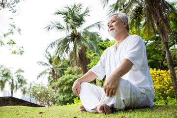 Naklejka na ściany i meble Elderly Asian man relaxing after yoga session in his backyard. Concept of staying healthy and living after retirement. Calm and assertive mind