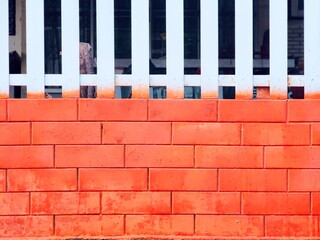 Orange wall background with white picket fence of a house.