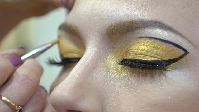 Slow Motion Beauty makeup. Makeup artist applies eye shadow.