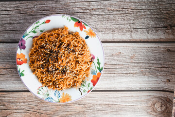 Noodles or spicy Hakka Noodles or Chow Mein in white plate at wood background. Schezwan Noodles is indo-chinese cuisine hot dish with udon noodles, seaweed and chilli sauce.