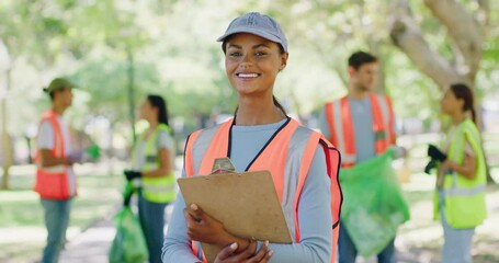 Female volunteer with a clipboard in the park leading a group of responsible activists doing charity work by cleaning up litter in the community. Caring for a sustainable, clean and safe environment