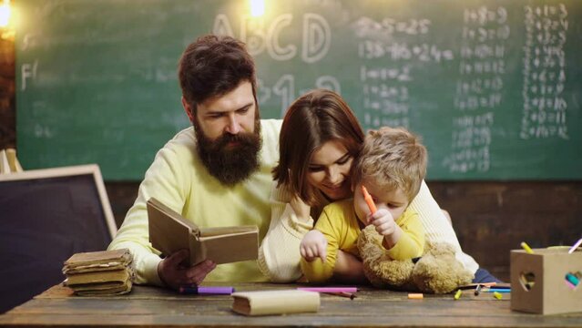 Cute clever boy study. Young mother father and little preschooler boy sit at table drawing together, playing, painting pictures in notebook, early development.