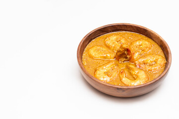 Bengali Dish or Food - Delicious authentic Bengali Prawn Malai Curry also known as chingri malai curry served on a wooden bowl. Traditional Goan Prawns or Shrimp curry. top view white background.