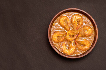 Bengali Dish or Food - Delicious authentic Bengali Prawn Malai Curry also known as chingri malai curry served on a wooden bowl. Traditional Goan Prawns or Shrimp curry. top view black background