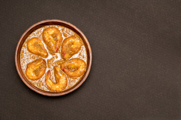 Bengali Dish or Food - Delicious authentic Bengali Prawn Malai Curry also known as chingri malai curry served on a wooden bowl. Traditional Goan Prawns or Shrimp curry. top view black background.