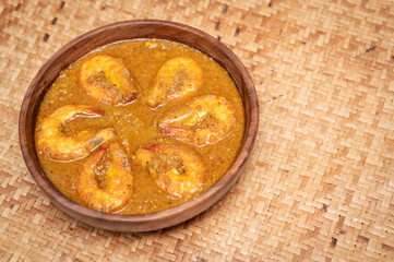 Bengali Dish or Food - Delicious authentic Bengali Prawn Malai Curry also known as chingri malai curry served on a wooden bowl. Traditional Goan Prawns or Shrimp curry. top view matt background