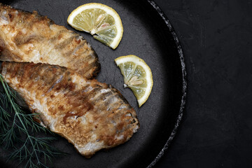 fried fish with lemon and herbs in a frying pan on the table copy space
