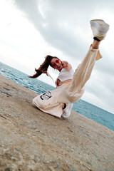 Female hip-hop dancer smiling while making a freestyle dance pose against sea.