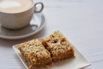 Natural turkish baklava and cup of cappuccino on wooden table outside. Coffee break on the cafe terrace