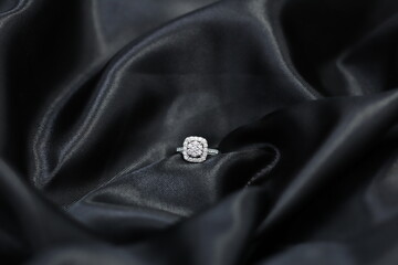 Fine jewelry as diamond ring with diamond with black satin fabric background. Jewelry shop concept