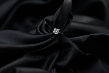 Fine jewelry as diamond ring with diamond with black satin fabric background. Jewelry shop concept