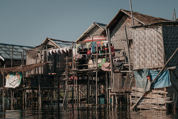 Burmese style wooden houses on stilts on Inle Lake in Myanmar on a sunny day.