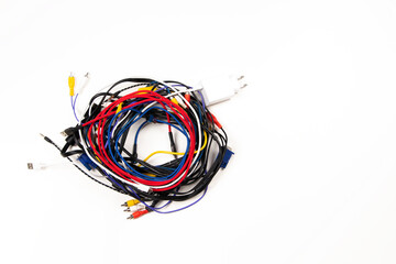 Many colorful electrical cord wires cord cables twist coiled into pile on white background. Top view
