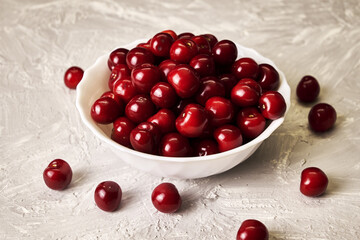 red ripe cherries in a white plate on the table
