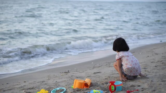 Little kid play sand near her beach tool