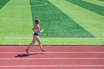 Fototapeta premium Young caucasian woman is engaged in jogging at the stadium outdoors.