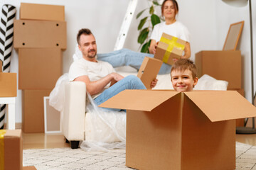Parents and son packing boxes and moving into a new home