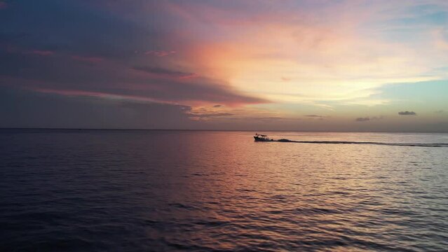 Alone boat in Mexican caribbean multicolored sunset and backlighting
people