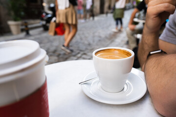 Close up photo of hands holding a cup of coffee in street cafe