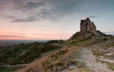 Mow Cop Castle, Cheshire / Staffordshire, England in sunlight with blue sky, clouds and distant landscape; landscape format.
