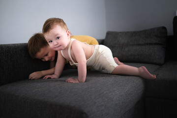 Sibling children play on sofa in living room together