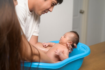 New born having a bath by happy mother and father, family and love concept