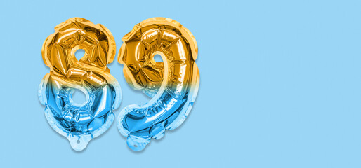 Rainbow foil balloon number, digit eighty nine on a blue background. Birthday greeting card with...
