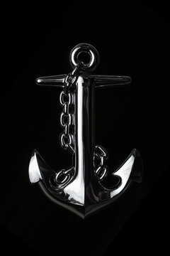 Shiny anchor with chain on black background..