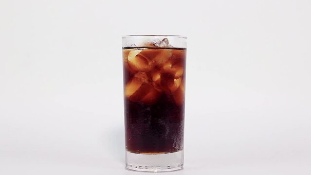 Glass of cola with ice is filled with black cola on white background