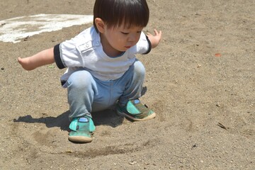 公園の地面で遊ぶ幼児　2歳