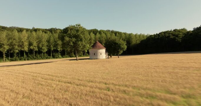 Aerial view of the chapel of the Liget next to wheat fields during sunset in France.