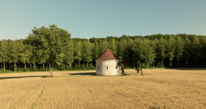 Aerial view of the chapel of the Liget next to wheat fields during sunset in France.