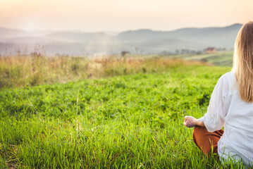 Woman doing yoga on the green grass at the mountain. Carpathians