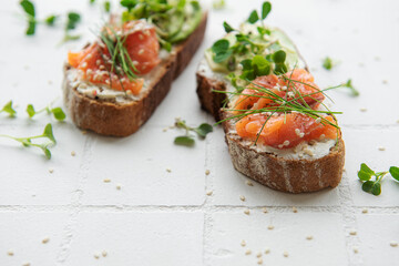Sandwiches with salted salmon,  avocado and microgreens.