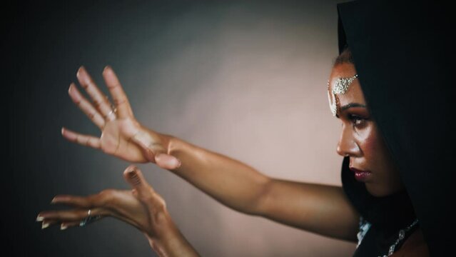 Closeup portrait fantasy african american woman voodoo witch conjuring ritual traditional. Art dance hands. Girl goth vampire dances hypnotizes sexy finger slow motion. mystical face. Black dress hood