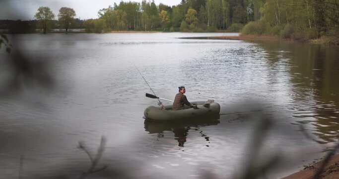 Beautiful cinematic shot. Girl fisherman rowing oars on lake an inflatable boat.