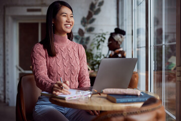 An Asian girl follows online lectures on the laptop at a cafe.