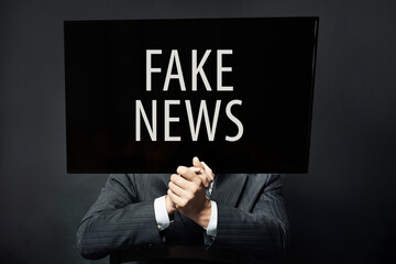 Businessman with TV head standing on black background. Fake news, lie and manipulation concept