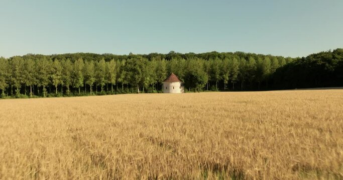 Aerial view of the chapel of the Liget next to wheat fields during sunset in France.