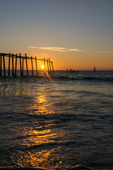 Obraz premium Sunrise through a fishing pier at the beach