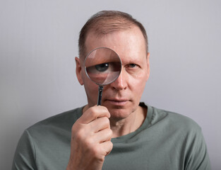 Man looking through magnifying lens glass portrait. High quality photo
