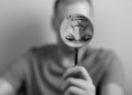 Psychology concept of distorted self perception. Man with magnifying glass and upside down fake reflection. High quality photo