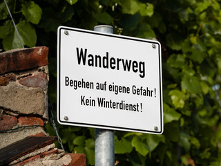 Wanderweg (hiking trail) sign in the nature. The text in German language says the use of the...