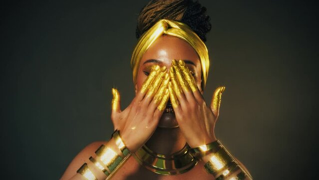 fantasy art portrait blue eyes close up, face african american woman. Professional golden metallic make-up shiny shadows. Hands in golden liquid drops flow. Fashion model girl. Studio black background