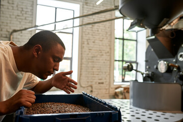Black barista sniffing fresh roasted coffee beans