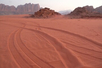 Fototapeta na wymiar Amazing scenery of Wadi Rum Desert looks like Mars. Traces of off-road car tires on red sand.